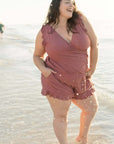 Woman enjoying the beach in a pink one-piece swimsuit, showcasing a relaxed summer vibe.
