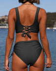 Back view of a woman in a stylish strappy bikini swimsuit by the beach, showcasing comfortable women's swimwear.