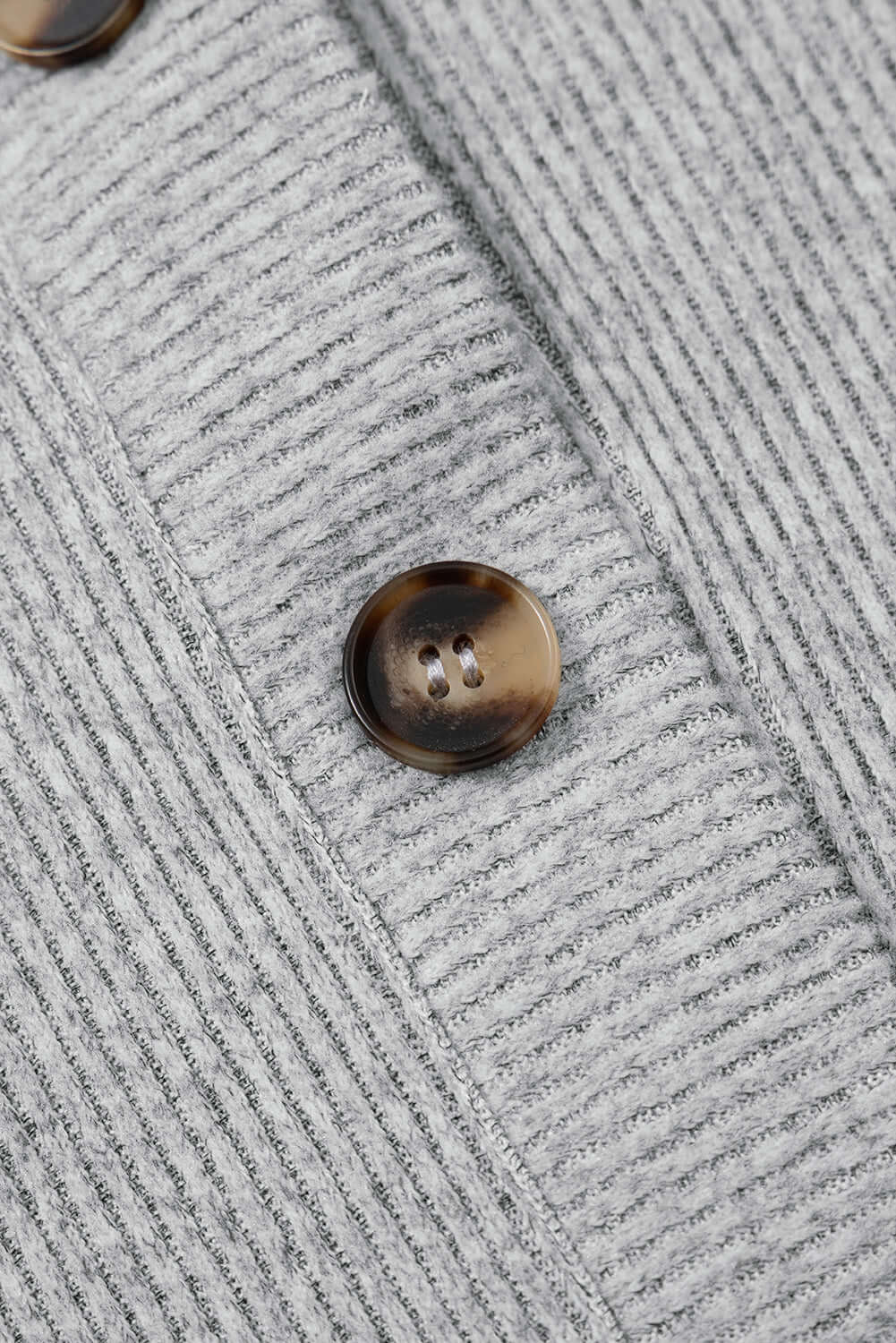Close-up of a light grey ribbed fabric showcasing a round button detail, ideal for women's lounge wear.
