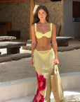 Stylish woman in a yellow printed bikini and matching skirt, perfect for summer beach days in women's swimwear.
