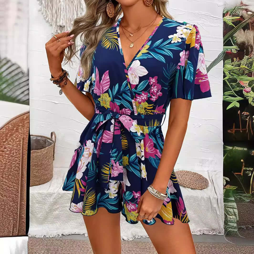 Woman wearing a floral printed navy jumpsuit with ruffle sleeves, perfect for summer beach vacations.