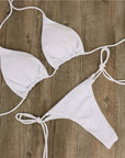 White halter neck tie bikini set on wooden background, perfect for women's swimwear fashion.