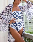 Model wearing a floral printed one-piece swimsuit with a flowy cover-up, showcasing women's swimwear style.