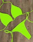 Vibrant neon green halter neck bikini set for women's swimwear on a wooden background.