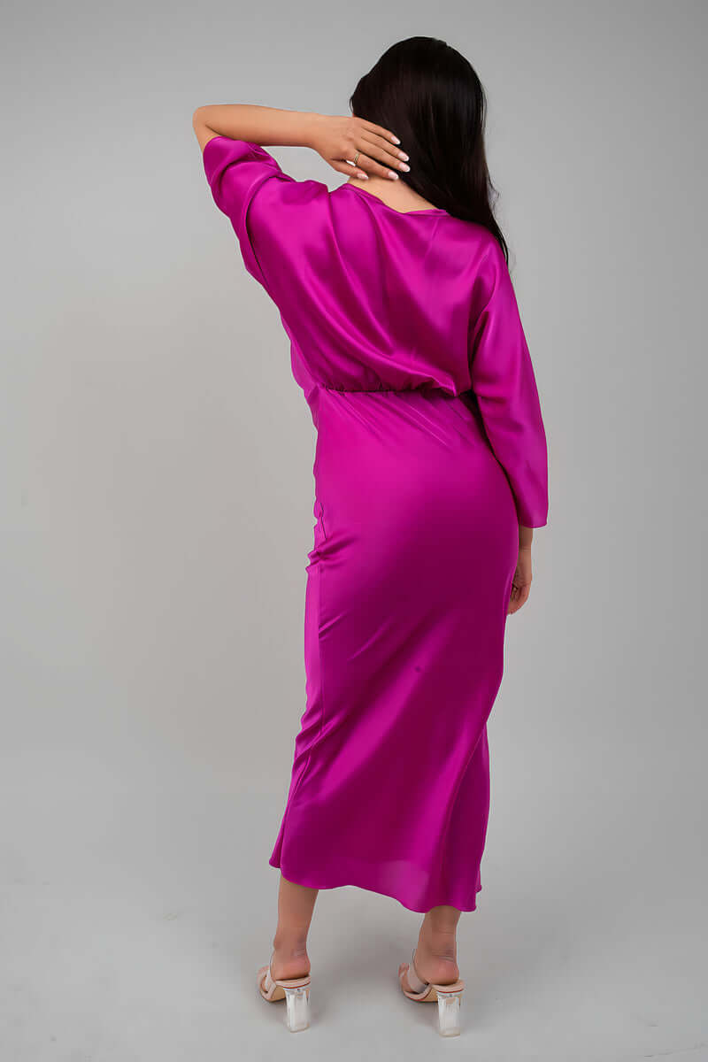 Back view of a model in a vibrant pink satin midi dress, showcasing relaxed fit and stylish design.