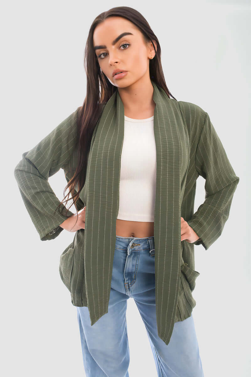 Person wearing an oversized green striped cardigan with pockets, styled with a cropped top and jeans.
