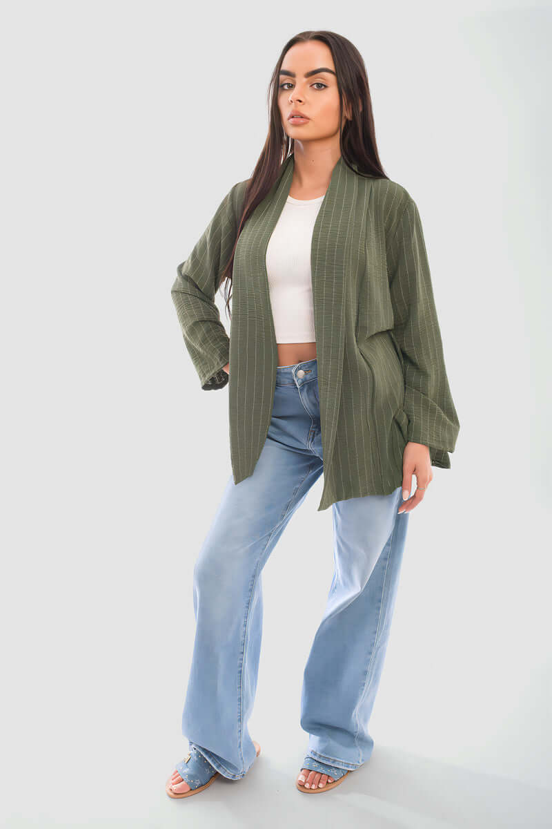 Model wearing an oversized olive green cardigan with wide-leg jeans and a white crop top.
