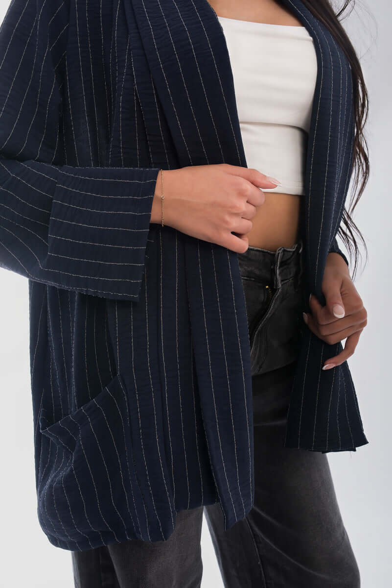Model wearing an oversized striped long sleeve cardigan with pockets, styled with a crop top and high-waisted pants.