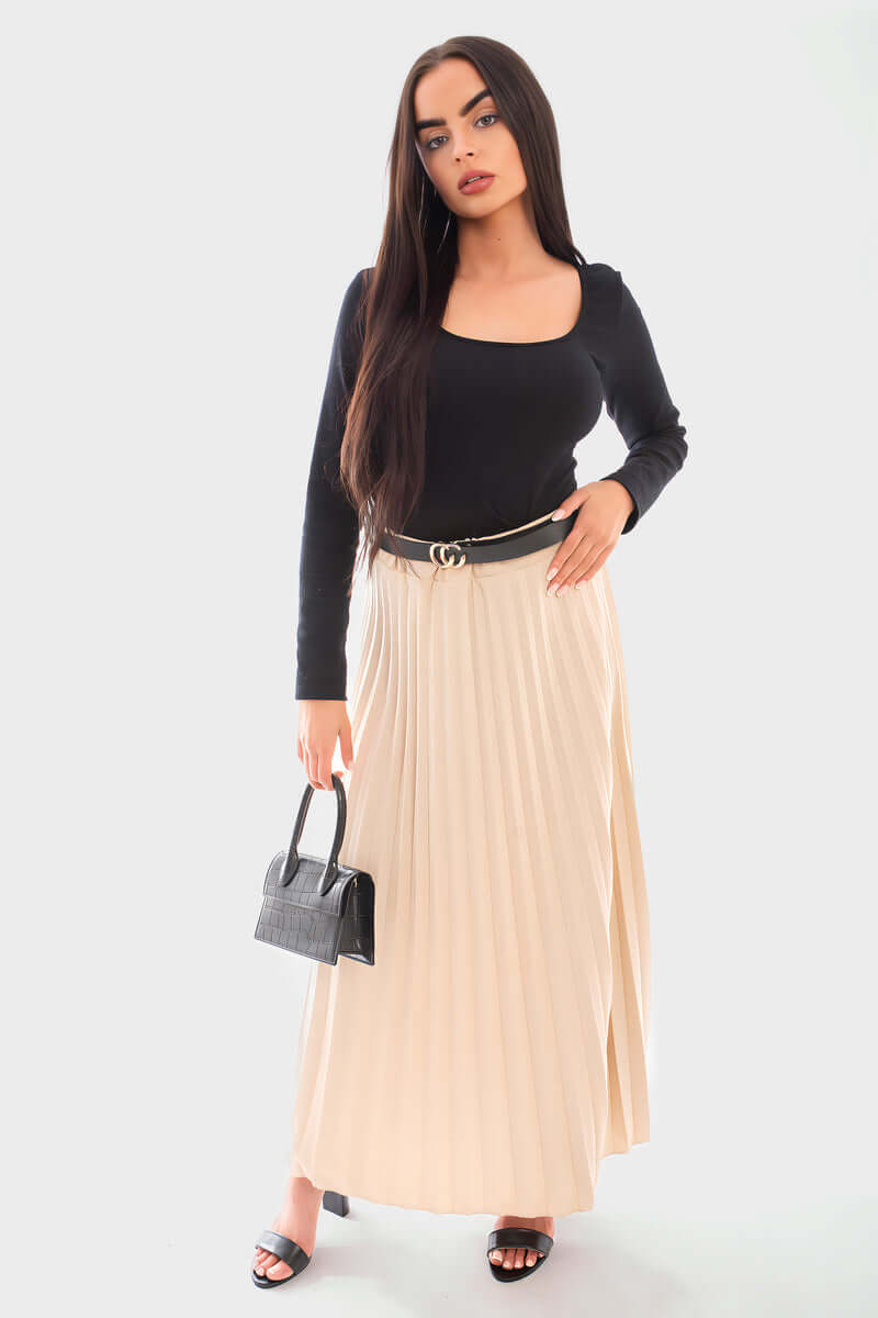 Belted maxi length pleated skirt in beige, styled with a black long-sleeve top and small handbag.