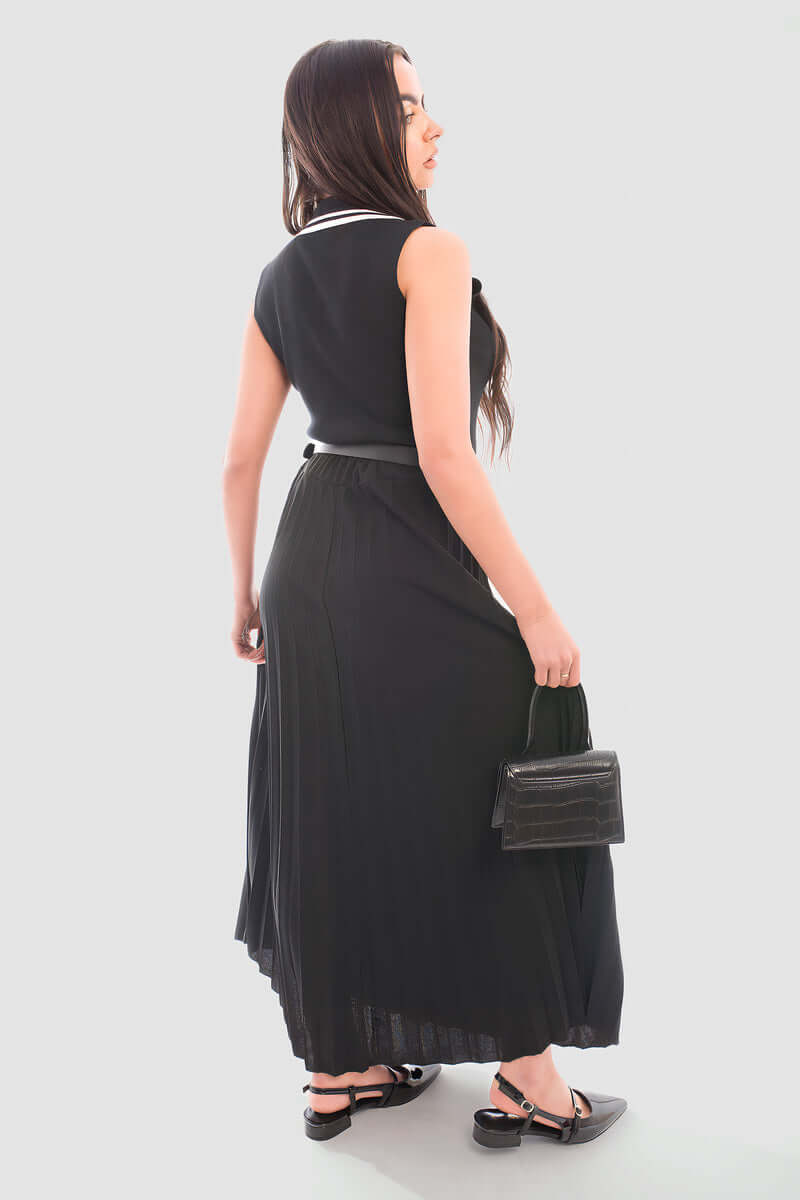 Back view of a model wearing a belted maxi length pleated skirt made of organic cotton, showcasing its relaxed fit.