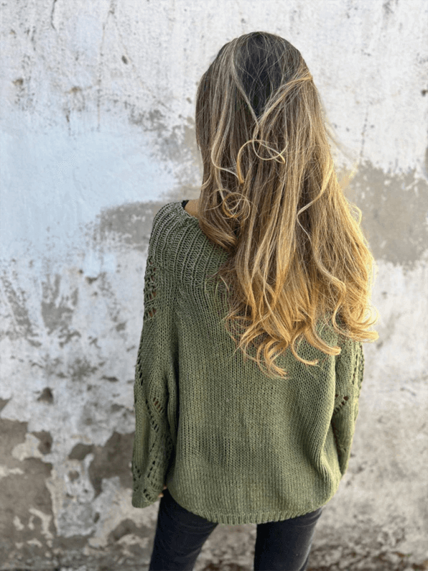 Back view of a model wearing a loose green knit sweater with long hair, showcasing a casual autumn style.