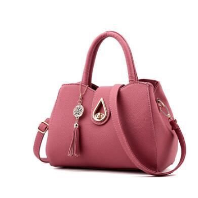 Stylish pink women's handbag made of high-quality PU leather with tassel detail and zipper closure.