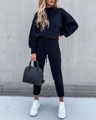 Casual high neck long sleeve black trousers two-piece suit outfit with handbag and white sneakers.