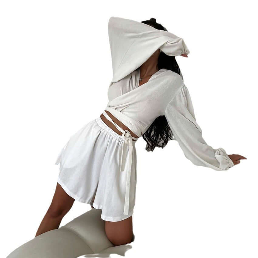 Young woman in white two-piece cotton pajamas, featuring shorts and a trendy wrap top, perfect for casual wear.