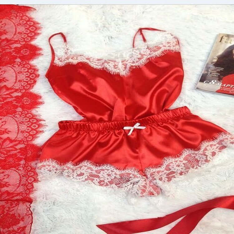 Red lace-trimmed satin women's pajamas set flat lay on a soft background, showcasing elegant sleepwear.