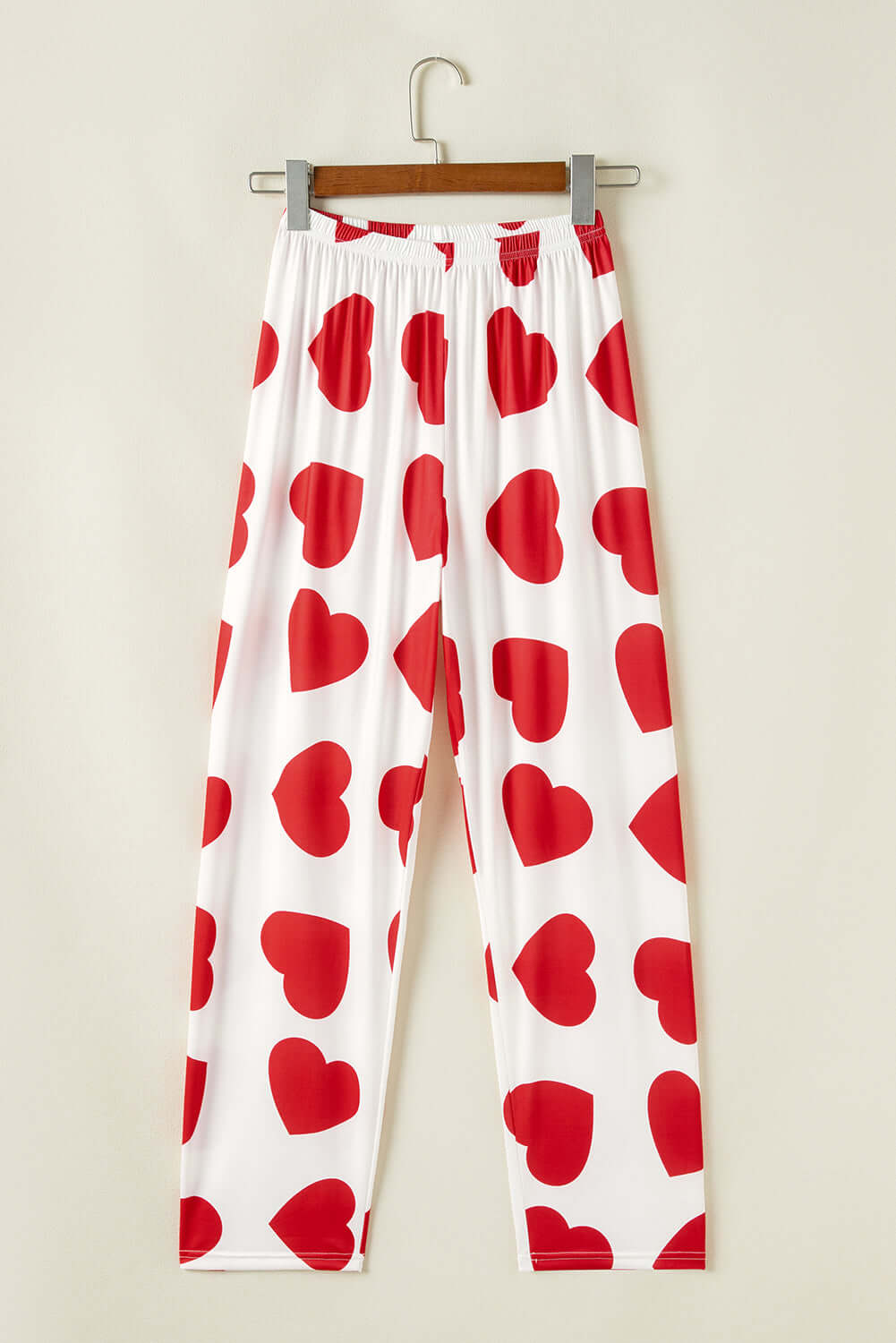 Red heart print lounge pants hanging on a hanger, perfect for women's pjs from Little Miss Vanilla clothing UK.