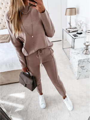 Casual high neck long sleeve two-piece suit in beige with pockets, styled with white sneakers and a chic handbag.