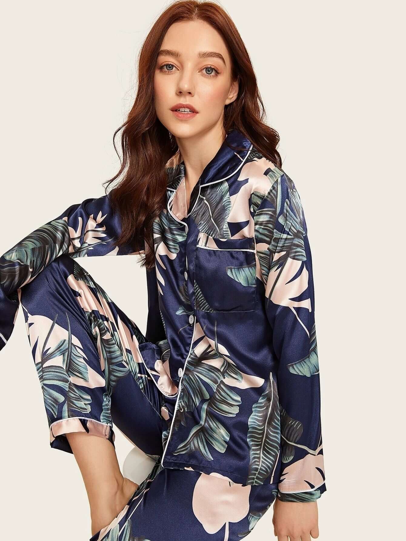 Stylish women in women's pjs, wearing two-piece stretch satin homewear with tropical leaf print.