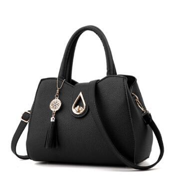 Stylish women's handbag in black PU leather with tassel and decorative charm, featuring a shell shape and zipper closure.