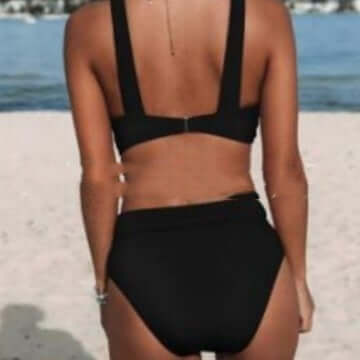 Woman in a black slim bikini by the beach, showcasing stylish women's swimwear perfect for summer.