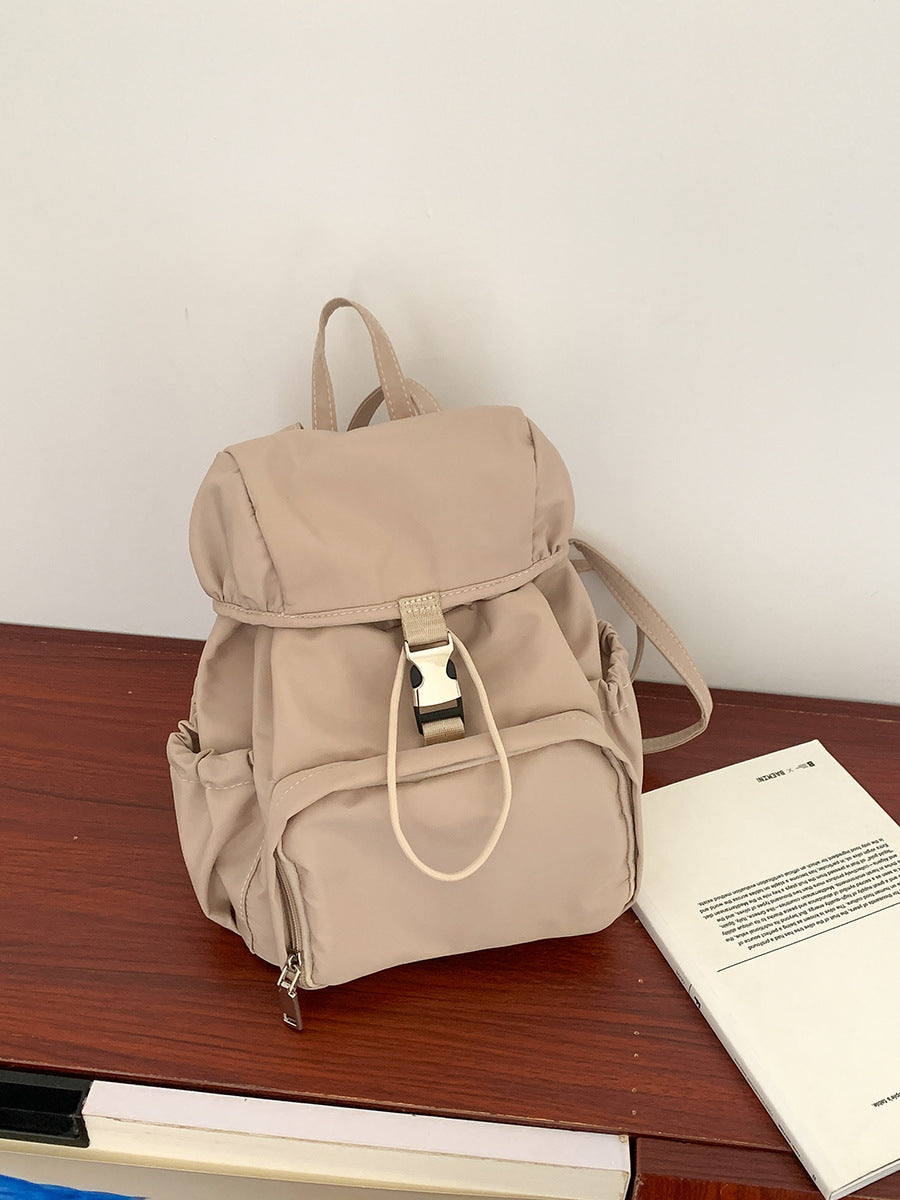 Simple small nylon backpack in beige, perfect for casual use or school, featuring adjustable straps and multiple pockets.