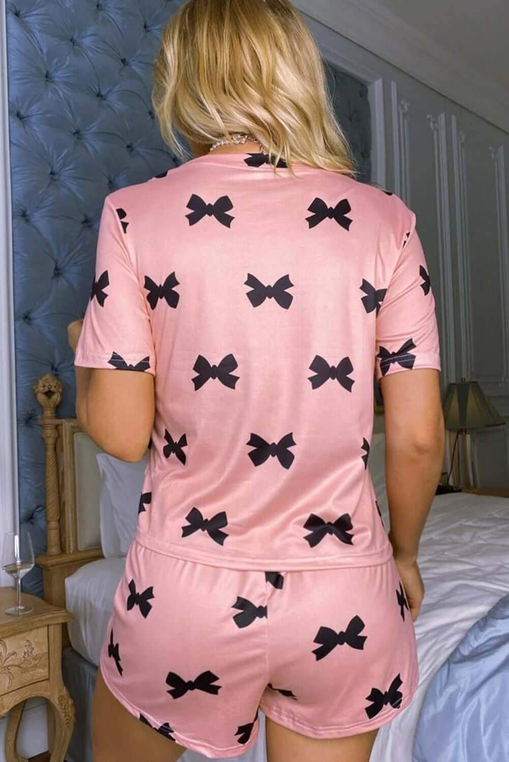 Back view of a women's pink bow printed short lounge set, showcasing playful black bow design.