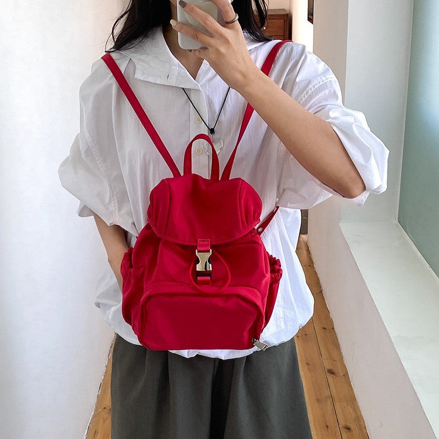 Trendy red nylon backpack displayed worn casually, ideal for school or casual outings, featuring adjustable straps.