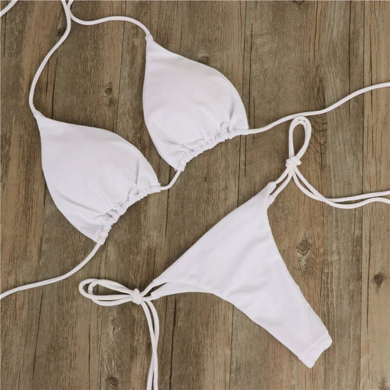 White halter neck tie bikini set on wooden background, perfect for women's swimwear fashion.