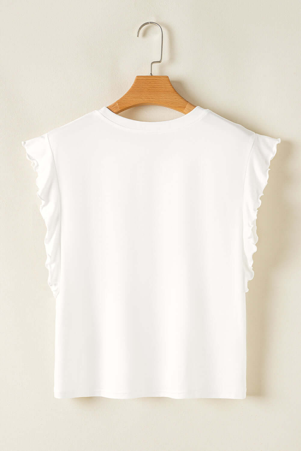 Back view of a white women's ruffled tank top hanging on a wooden hanger, showcasing a simple and elegant design.
