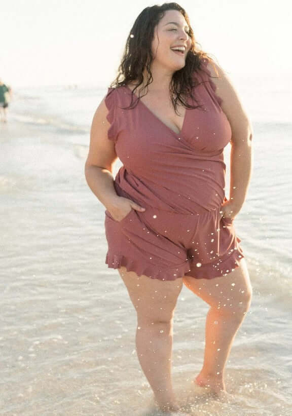 Woman enjoying the beach in a stylish summer romper, featuring a playful design and comfortable fit.