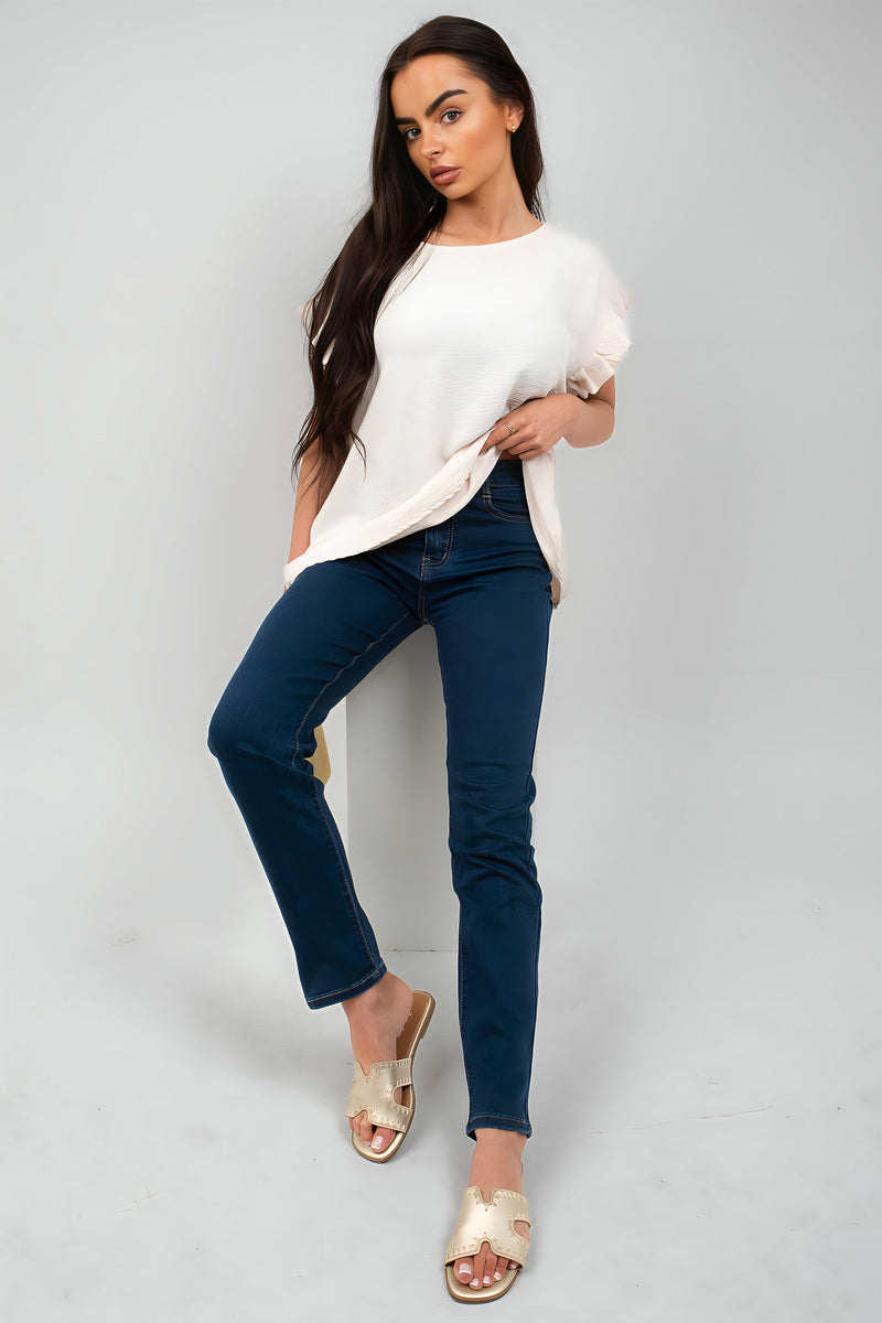 Woman in straight leg high waist jeans paired with a white top and sandals, showcasing casual style.