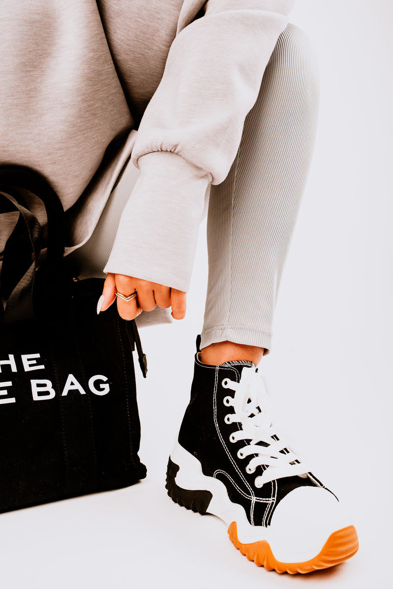 Stylish chunky platform round toe lace up trainers paired with casual gray leggings and a black tote bag.