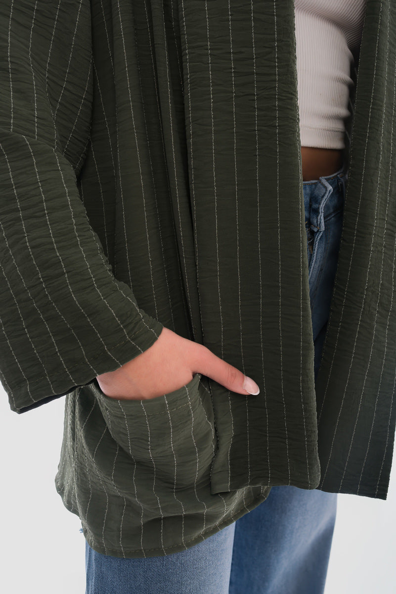 Close-up of a cozy oversized green striped cardigan with pockets, paired with casual blue jeans.