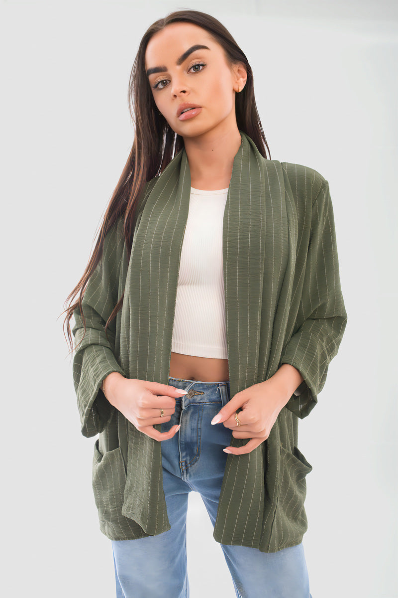 Oversized striped long sleeve cardigan in green with pockets, styled over a white top and blue jeans.