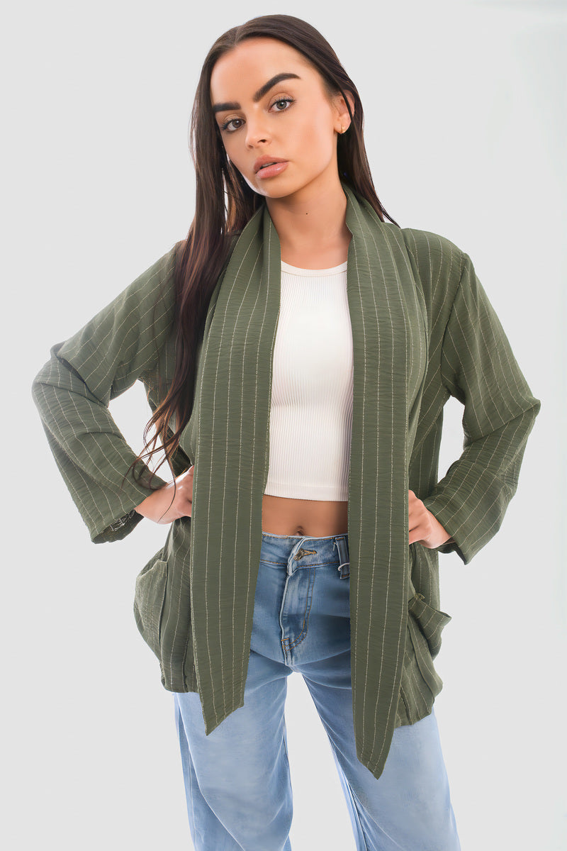 Person wearing an oversized green striped cardigan with pockets, styled with a cropped top and jeans.