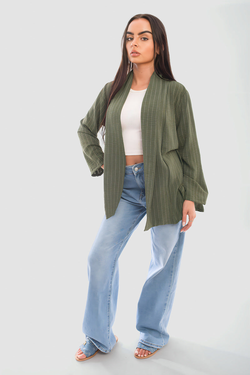 Model wearing an oversized olive green cardigan with wide-leg jeans and a white crop top.
