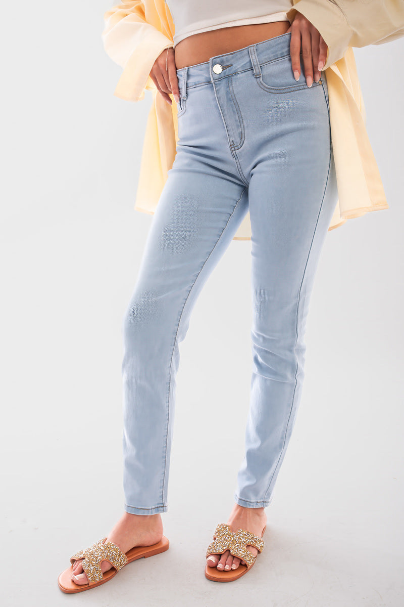 Woman wearing light blue high waisted skinny fit jeans paired with stylish sandals and a light top, showcasing a trendy look.