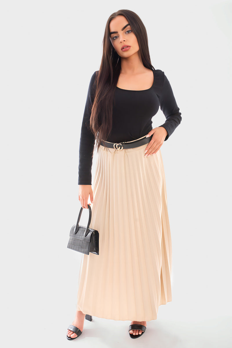 Belted maxi length pleated skirt in beige, styled with a black long-sleeve top and small handbag.